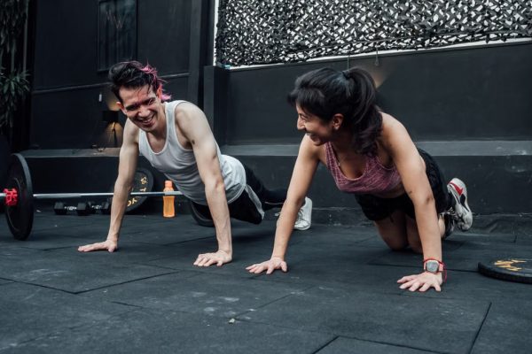Man and woman doing pushups while smiling during a workout inside a Mexico City gym.